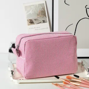 Detailed view of large pink striped seersucker cosmetic bag with professional makeup brushes.