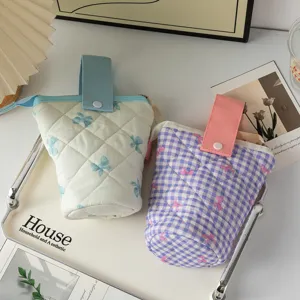 Gros plan de trousses à crayons matelassées à motifs de nœuds en crème et violet.