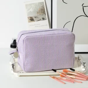 Large capacity purple striped seersucker cosmetic bag displayed with makeup brushes