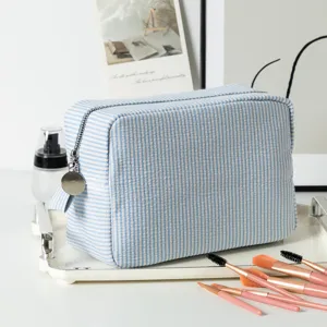 Blue and white striped seersucker cosmetic bag with makeup brushes on a tray