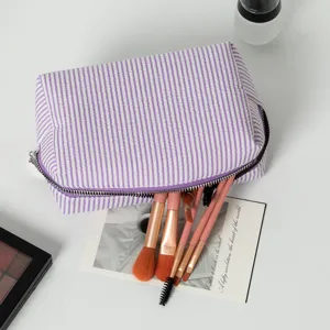 Detailansicht der lila gestreiften Seersucker-Kosmetiktasche mit Make-up-Pinseln drin