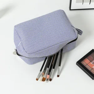 Close-up of blue and white striped seersucker makeup bag with brushes