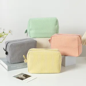 Seersucker striped cosmetic bags in various colors on display props.