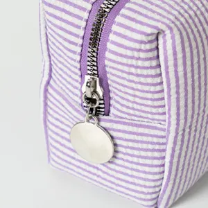 Detailansicht der Kosmetiktasche aus Seersucker mit lila Streifen und Reißverschluss.