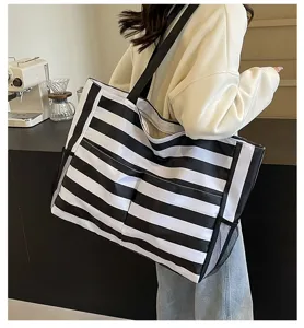 Detailansicht einer großen gestreiften Strandtasche, die an der Schulter hängt.