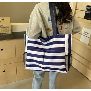Große blau-weiß gestreifte Einkaufstasche, präsentiert von einem Model im Alltag.