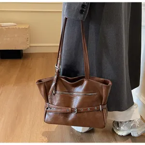 Detailed side view of a vintage brown soft leather tote bag with buckle accents
