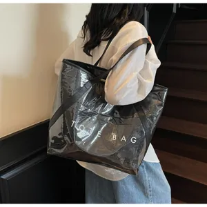 Stilvolle Frau mit großer transparenter PVC-Tragetasche mit TOTE BAG-Aufdruck im Innenraum