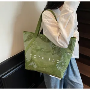 Nahaufnahme einer grünen transparenten PVC-Tragetasche mit weißem TOTE BAG Aufdruck