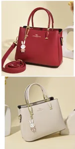 Detailed view of elegant red and beige leather handbags featuring a cute rabbit pendant