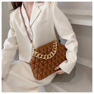 Braune gesteppte Leder-Pouch-Tasche mit goldener Kette in modischem Outfit-Setting.