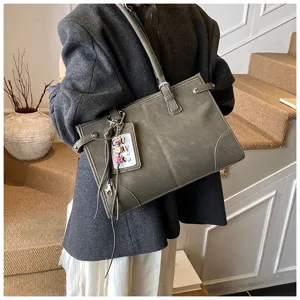 Vintage large capacity olive green tote bag carried on shoulder by a model in a blazer