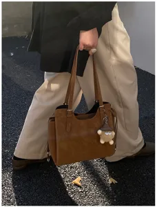 Fashionable brown soft leather tote bag for women shown in a casual street setting