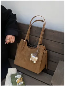 Large brown soft leather tote bag on wooden bench with autumn commute accessories