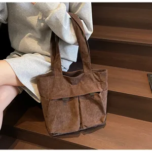 Close-up detail view of the brown corduroy tote bag showcasing multiple pockets and sturdy handles.
