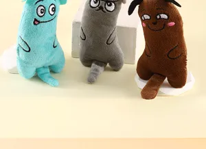 Dettaglio di peluche per gatti colorati con code lunghe, carta stropicciata ed erba