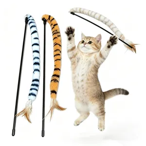 Action shot of a kitten jumping for a tiger-striped plush cat teaser wand with feathers.
