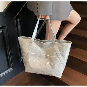 Große Tragetasche aus grauem Dupont-Papier mit minimalistischem TOTE BAG Aufdruck für Damen
