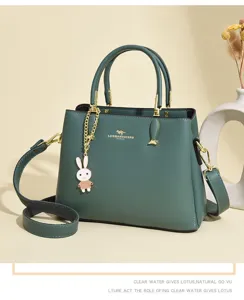 Detailed view of dark green leather handbag featuring golden logo and cute rabbit charm detail