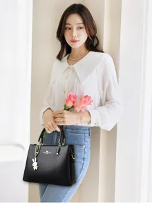 Elegant black leather handbag held by a woman in a bright, modern indoor lifestyle setting