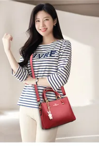 Elegant red leather handbag for weddings, worn by a model in a bright indoor setting.