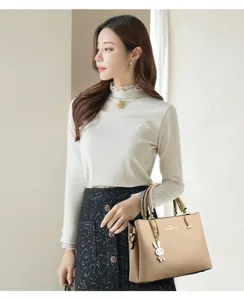 Elegant beige leather handbag for women featuring a cute rabbit charm accessory and gold hardware