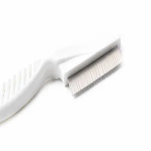 Détail macro des dents serrées en acier inoxydable d'un peigne anti-puces blanc pour animaux
