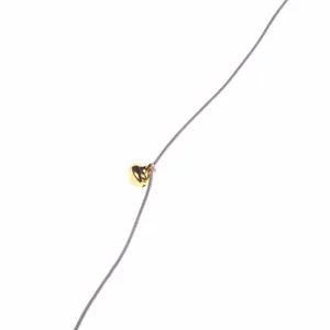 Close-up detail of a golden bell on a purple elastic string for cat teaser wand.