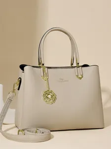 Elegant beige leather handbag for women, top handle tote with shoulder strap and chic flower charm.
