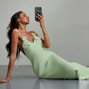 Solid color knit maxi beach dress with crochet flowers, elegant halter neck design for women.