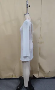 Détail latéral d'une robe de plage unie blanche à manches longues et dos nu.