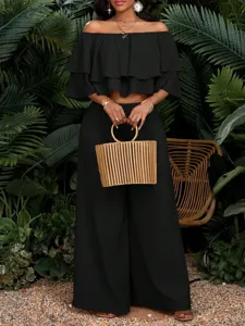 Detailaufnahme des schwarzen schulterfreien rüschen crop tops und der langen hose.
