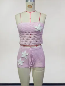 Ensemble crop top et short en tricot rose avec des applications de fleurs blanches.