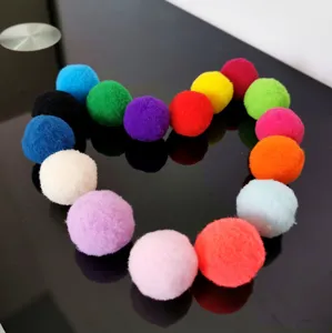 Close-up van kleurrijke 3 cm polyester pompons in een hartvorm op een zwart glazen oppervlak