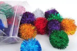 Dettaglio macro di pompon glitterati da 3cm per gatti che escono dalla confezione per giocare