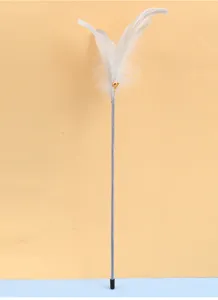 Primo piano di una bacchetta per gatti minimalista con morbide piume bianche e campanellino d'oro