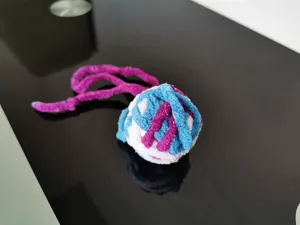 Primo piano di una palla giocattolo per gatti in filato colorato con una lunga coda viola