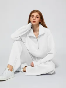 Detailed shot of women's solid white half-zip oversized sweatshirt and wide-leg sweatpants suit.