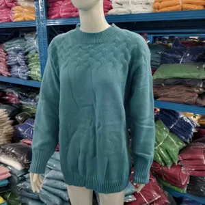 Détail de pull en tricot torsadé sarcelle, col haut et manches longues, texture classique.