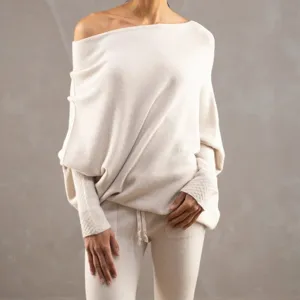 Gros plan sur le pull en tricot beige confortable avec encolure bateau et manches chauve-souris.