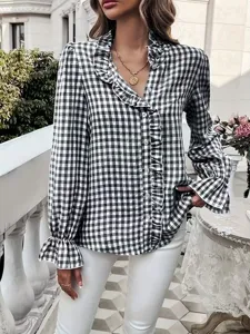 Detailaufnahme der stilvollen schwarz-weißen Karo-Bluse mit Rüschen und langen Ärmeln.