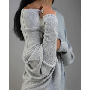 Détail de pull en tricot gris avec manches longues texturisées et tissu doux et confortable.