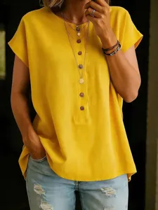 Close-up detail of casual yellow short sleeve button-up top and layered necklaces.