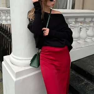 Élégant pull noir en tricot à épaules dénudées associé à une jupe rouge fashion détail.