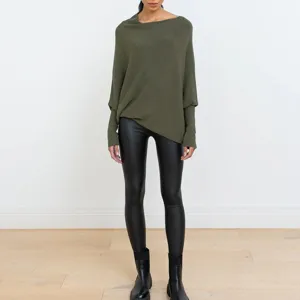 Vue détaillée du pull en tricot drapé asymétrique associé à un legging en cuir.