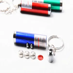 Gros plan sur le porte-clés pointeur laser miniature, boîtier métallique et piles boutons.