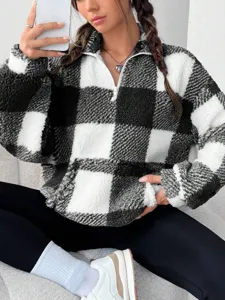Detail shot of black and white checkered sherpa half-zip fleece sweatshirt texture.