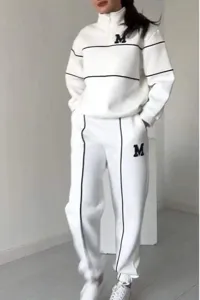 Detail view of the white half-zip sweatshirt and matching sweatpants set with black piping.