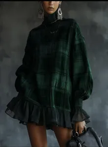 Detailed view of the dark green plaid long-sleeve dress with black mesh ruffle hem.