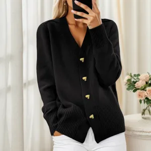 Detalle de cárdigan de punto negro con elegantes botones dorados de corazones y cuello en V.